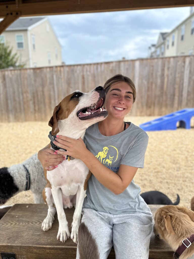 Staff member smiling with happy brown and white dog at Happy Dog Care for Dog Daycare near Columbia, MD